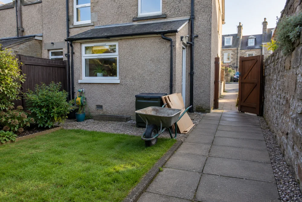 Clear paved side passage and open gate beside a terraced home